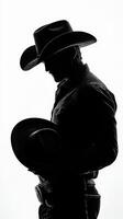 Cowboy silhouette holding a hat in a dramatic pose against a bright background photo