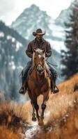 Cowboy riding a horse through a mountainous landscape during the day photo