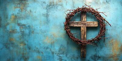 Rustic wooden cross adorned with a crown of thorns against a textured blue backdrop photo