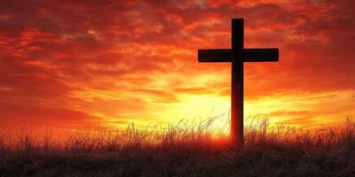 Cross silhouetted against a vibrant sunset sky with wispy clouds in a peaceful landscape photo