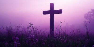 Cross silhouetted against a purple foggy landscape with flowers in a serene natural setting photo