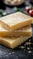 Homemade natural soap bars stacked on a dark surface with decorations in the background photo
