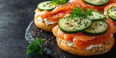 Delicious smoked salmon and cucumber on bagel bites served with herbs and sesame on a dark stone plate for an elegant appetizer photo