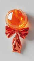 Bright orange candy with a shiny bow displayed on a light gray background photo