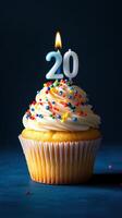 Celebrate a special milestone with a beautifully decorated cupcake topped with a lit candle for twenty years of joy photo