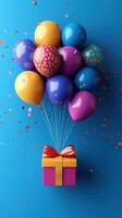 Colorful balloons with confetti and a gift box celebrate a festive occasion against a blue background photo