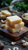 Creamy handmade soap bars stacked on a wooden board with cashews in a rustic setting photo