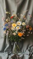 Vibrant bouquet of wildflowers arranged beautifully on soft fabric backdrop photo