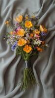 Beautiful floral bouquet of assorted wildflowers arranged on soft fabric background photo