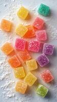 Colorful fruit-flavored candy squares arranged on a light surface with powdered sugar scattered around photo