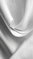 Delicate folds of soft white fabric drape gracefully in the light showcasing texture and movement photo