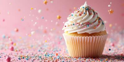 Colorful cupcake with frosting and sprinkles on pink background during celebratory event photo