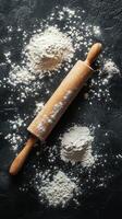 Flour scattered around a wooden rolling pin on a dark surface during baking preparation at a kitchen photo