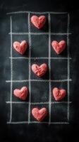 Creative Valentine's Day heart-shaped tic-tac-toe game using pink sand on a chalkboard background photo