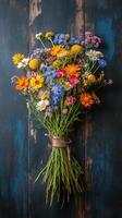 Brightly colored wildflower bouquet tied with twine resting on a rustic wooden surface photo