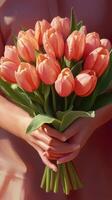 Holding a vibrant bouquet of pink tulips in warm light during a spring day photo