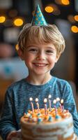 Joyful boy celebrating birthday with cake and party hat surrounded by warm lights photo