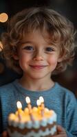 Joyful celebration of a young boy holding a birthday cake with lit candles in a cozy indoor setting during an evening gathering photo