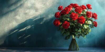 Bouquet of red roses displayed against a textured blue wall in soft light, highlighting their vibrant color and delicate petals photo