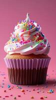 Delicious cupcake with colorful frosting and sprinkles on a pink background photo