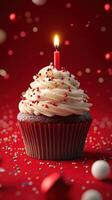 Cupcake with swirling frosting and candle against a vibrant red background, celebrating a special occasion with colorful sprinkles photo