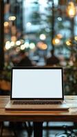 Laptop sits on a wooden table in a cozy cafe with blurred background and warm lighting photo