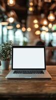 Working space with a laptop on a wooden table and a potted plant in a cozy cafe during daylight hours photo