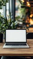 Modern workspace with empty laptop and greenery in a cozy cafe setting during daytime photo
