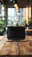 Laptop displaying code sits on wooden table in a well-lit cafe with greenery in the background photo
