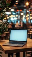 Laptop on wooden table in a cozy cafe with ambient lighting during a busy afternoon photo