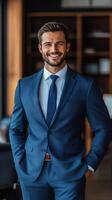 Confident businessman in blue suit smiling in modern office environment during daytime photo