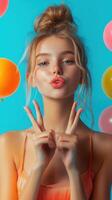Young woman makes a playful peace sign surrounded by colorful balloons in a vibrant blue setting photo