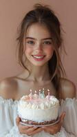 Celebratory moment of a girl holding a birthday cake with lit candles in a warm, inviting setting photo