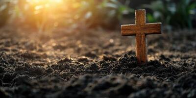 Wooden cross standing in soil during sunset in a quiet garden, symbolizing remembrance and reflection photo