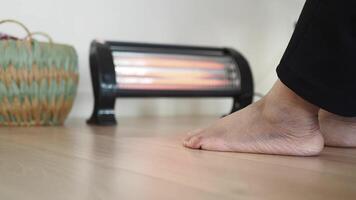 Enjoying warmth from a heater during a cozy indoor moment video