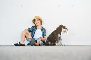 Smiling child with dog sitting against wall photo