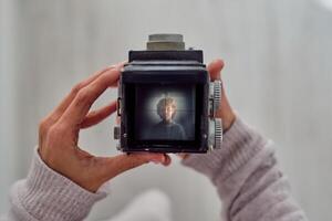 Crop photographer with photo of boy on retro camera display