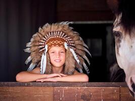 Smiling child in roach looking out of stable with horse photo