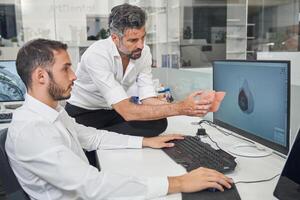 Workers checking 3D respirator near computer photo