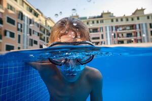Boy in diving mask swimming in pool in hotel photo