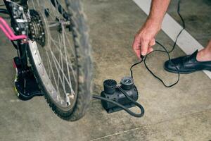 Old man inflating bicycle with compressor in garage photo
