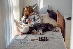 Boy with retro photo camera and Miniature Schnauzer on bed