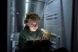 Boy with tablet sitting in fridge photo