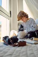 Boy with retro photo camera and purebred dog on bed