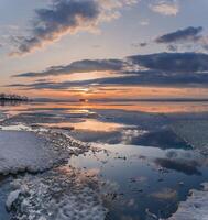 Winter. The surface of the ice is bound by ice, with a perfectly smooth, mirror-like appearance. Sunset in winter over the lake. photo