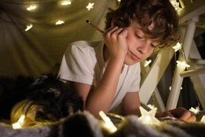 Content boy with pencil in blanket fort photo