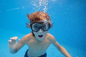 Boy with mouth opened swimming in pool photo