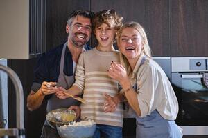 Happy family with faces dirty of dough cooking together at home photo