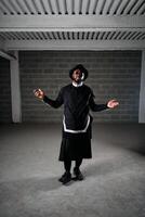 Man wearing dark clothes standing in studio photo