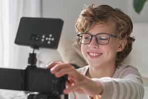 Positive boy setting up camera while recording for blog photo